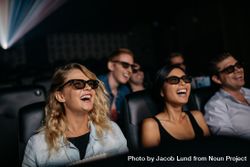 Group of friends watching 3d movie and laughing in cinema 56xPVb