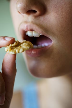 Crop anonymous teenage girl about to bite into a delicious walnut