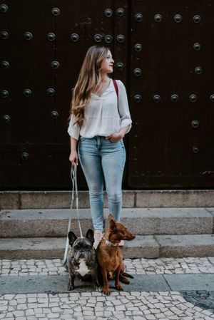 Stylish woman with dogs standing on street
