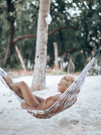 Woman wearing bikini relaxing on hammock