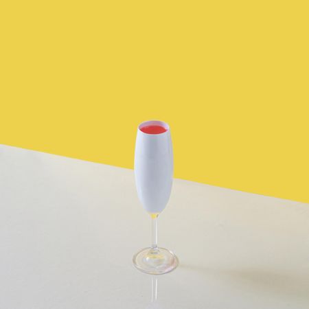 Champagne glass with pink drink against yellow and blue background