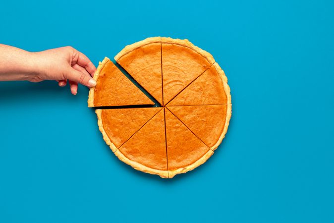 Woman hand taking slice of pumpkin pie
