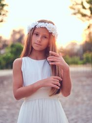 Tender child in dress touching hair in garden
