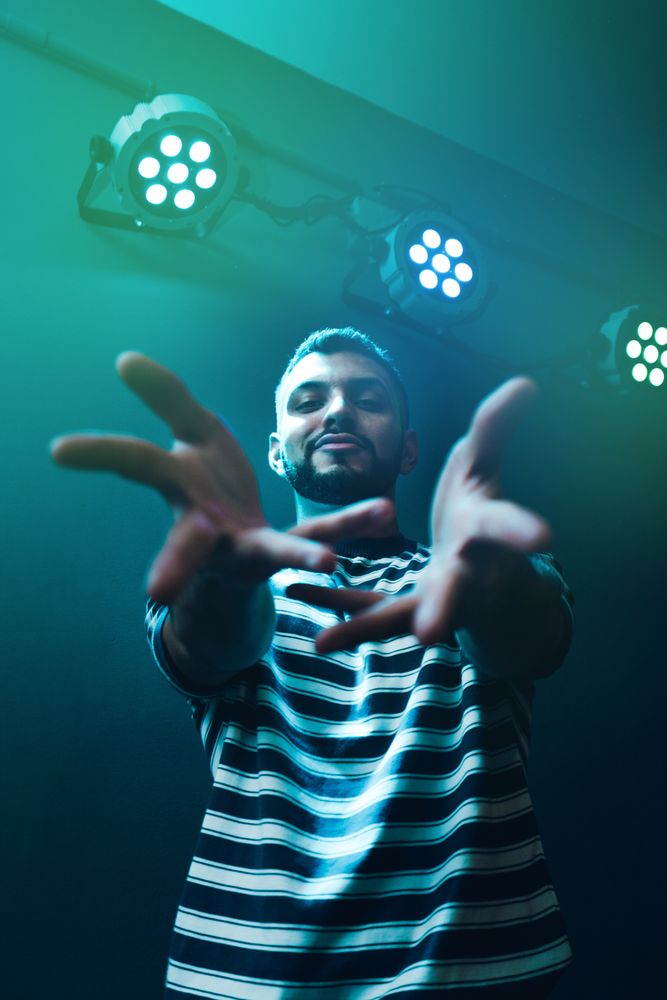 Man dancing in spotlight outstretching hand forward
