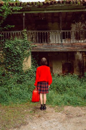 Woman in red with big red suitcase in forest
