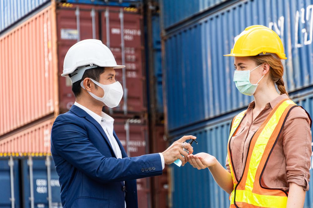 Logistic warehouse foreman giving alcohol gel onsite to worker