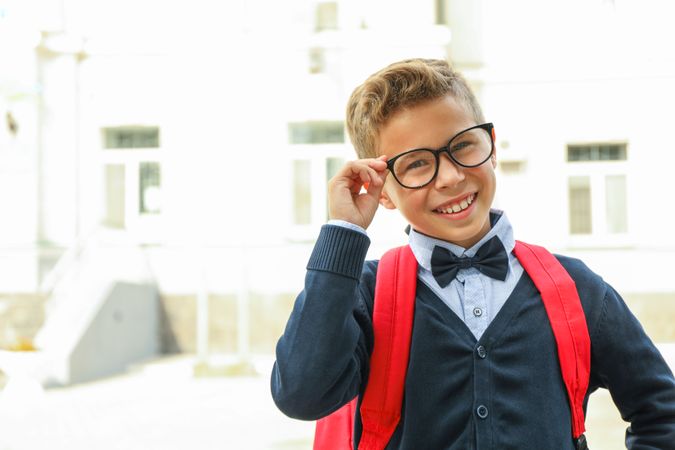 Boy with backpack against school building, space for text
