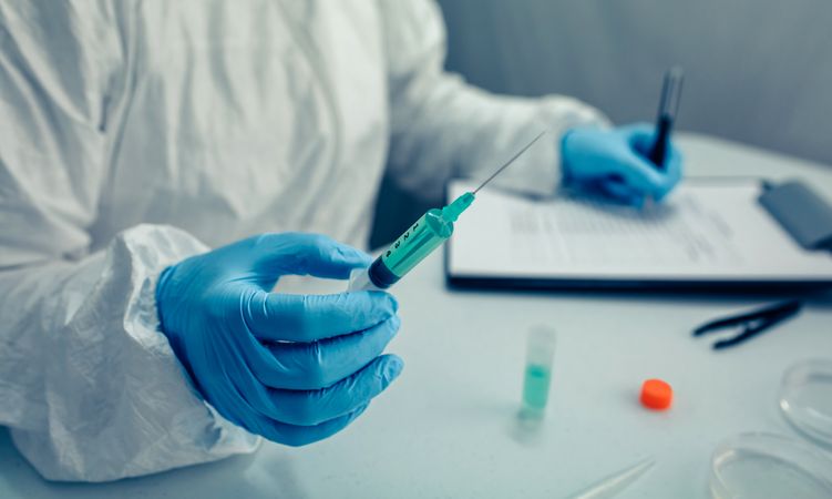 Scientist hand holding a syringe with virus vaccine