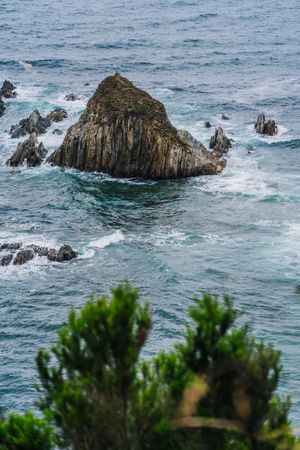 Rocky peaks surrounded by foamy water in windy day