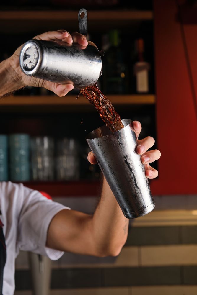 Unrecognizable barman mixing drink in pub
