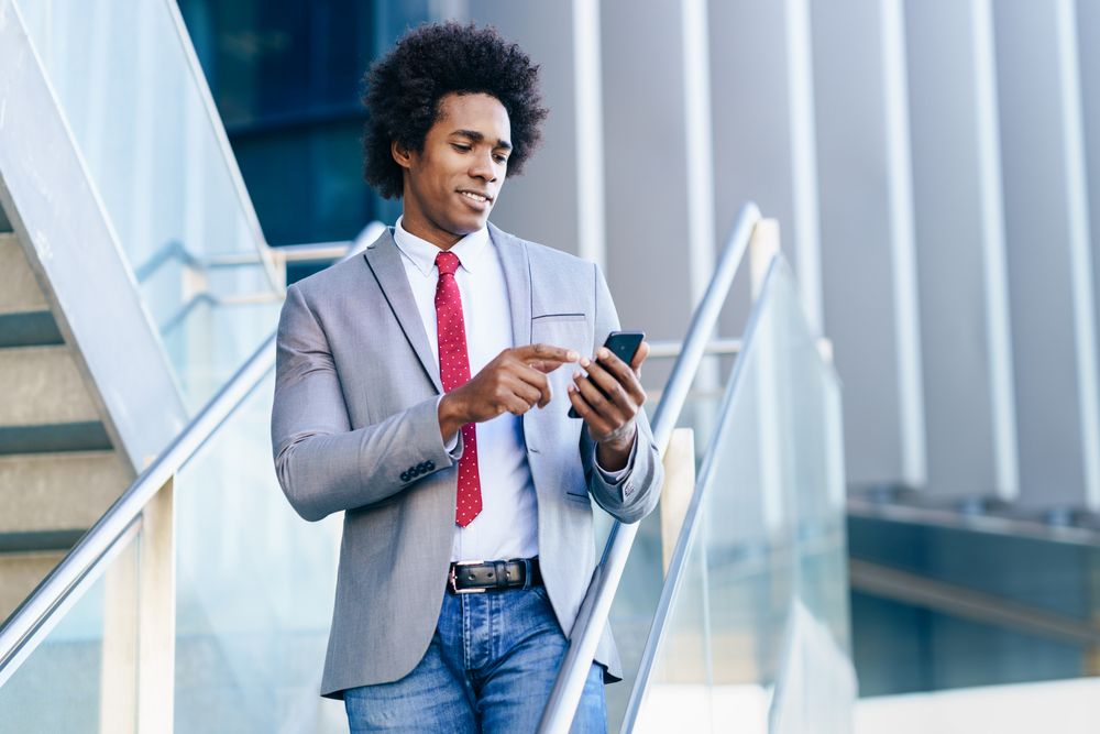 Happy man in business casual on stairs checking his phone