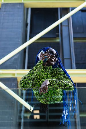 Black woman speaking on mobile phone in stylish wear in city