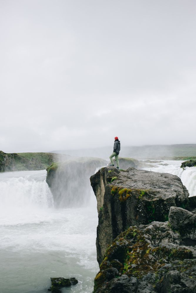 Man on cliff over waterfall, vertical