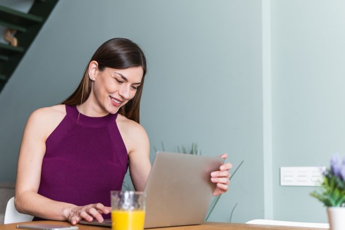 Cheerful woman browsing laptop in living room