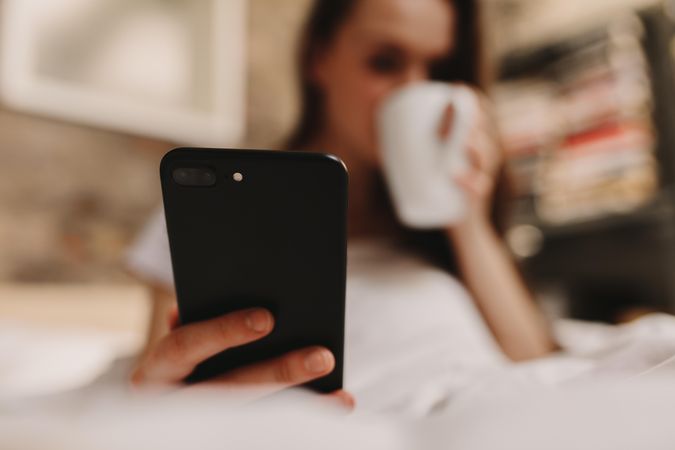 Woman looking at her mobile phone while having coffee