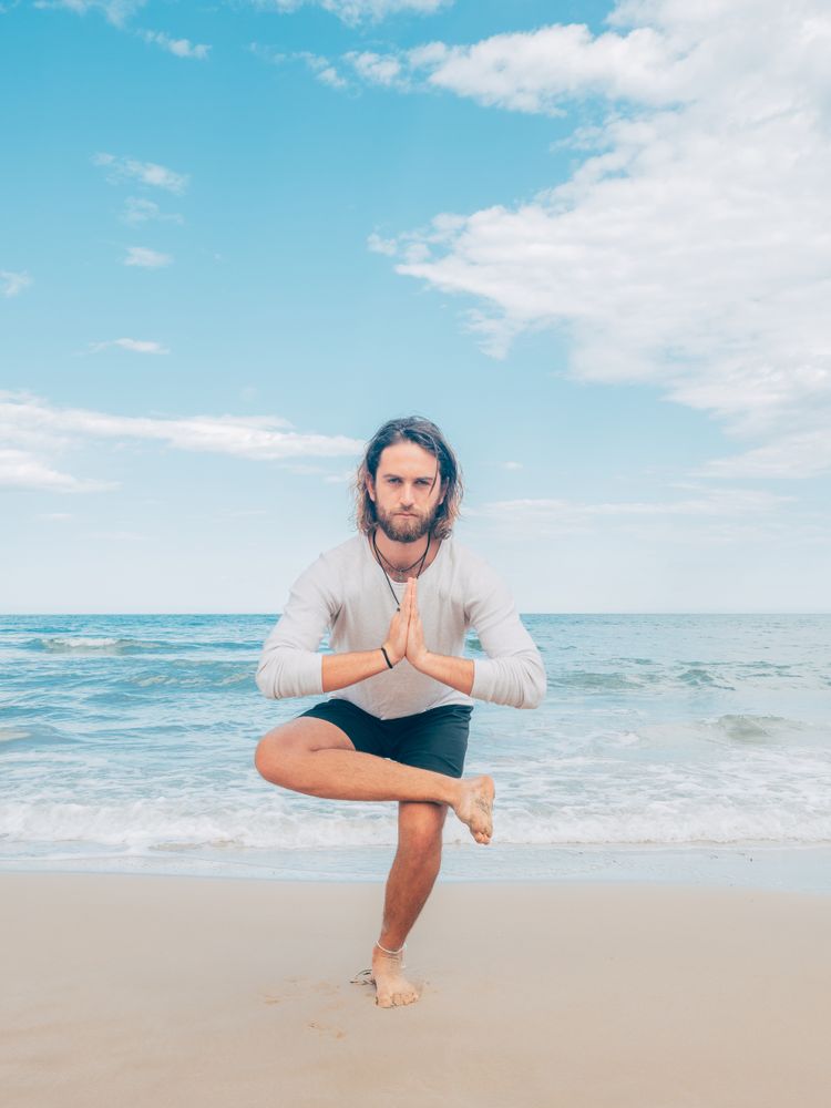 Man training yoga on beach