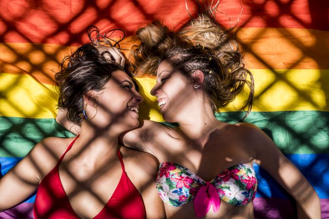 Lesbian couple lying on rainbow flag