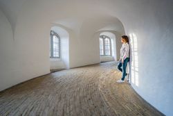 Casual woman leaning on wall in spacious gallery with windows