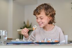 Cheerful boy eating rolls at home