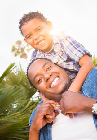 Son and Father Playing Piggyback Outdoors Together.