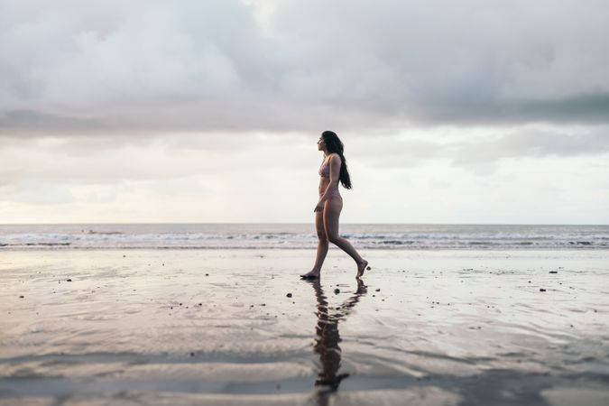 Brunette woman in bikini walking on the beach