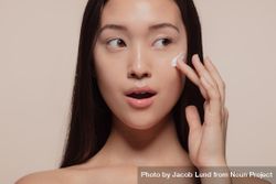 Woman applying moisturizer cream on her bare face bYw2Y5