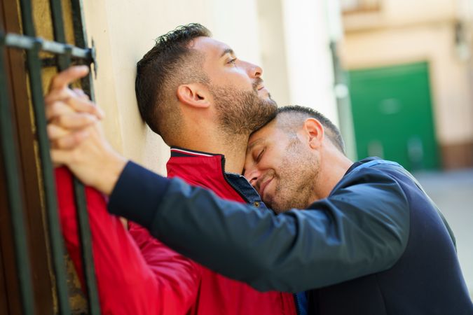 Two men in romantic embrace against building