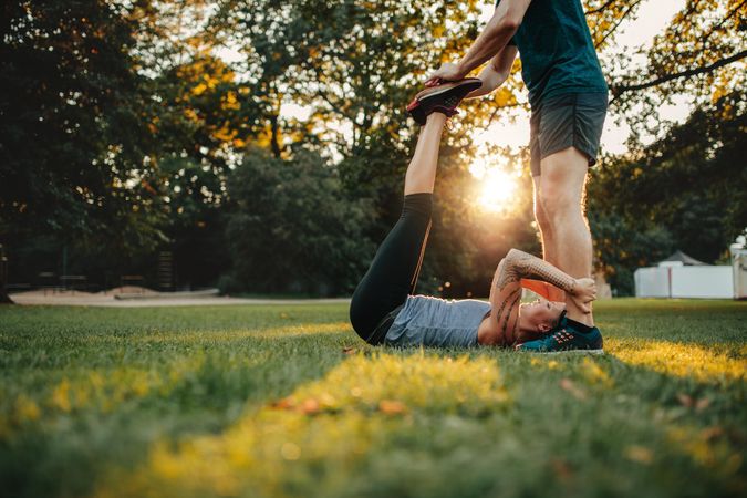 Side view of physical trainer helping woman do stretching workout