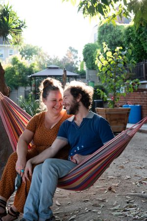 Woman looking lovingly at her partner sitting together outside in hammock