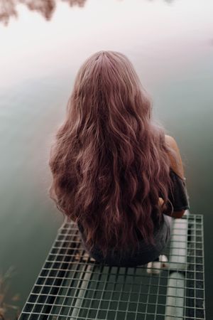 Stylish modern woman sitting on metal pier