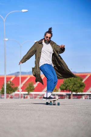 Stylish hipster man riding longboard in skate park