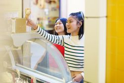 Two women buying ice cream cones on nice day