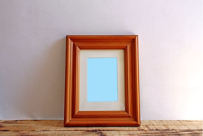 Rectangular wooden picture frame on wooden desk mockup