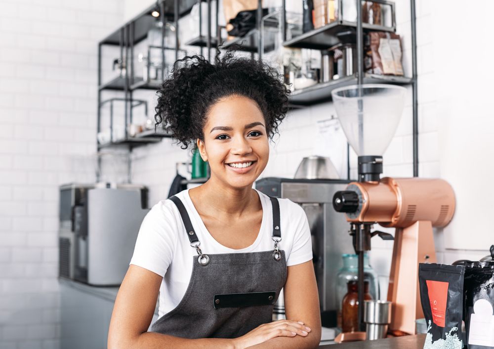 Smiling barista leaning on the counter of cafe