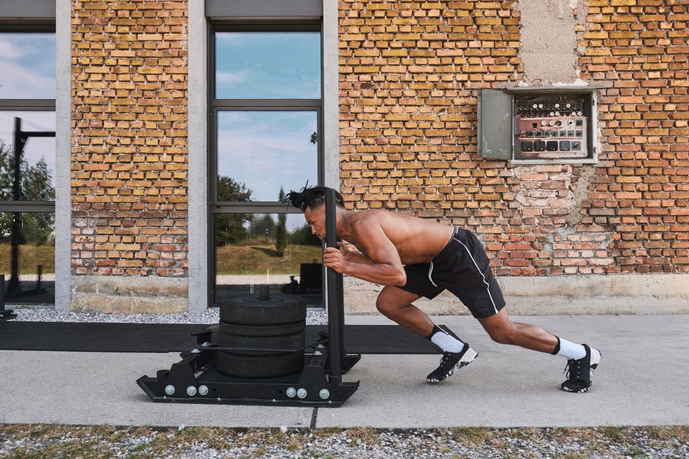 Black guy pulling weights in outdoor gym