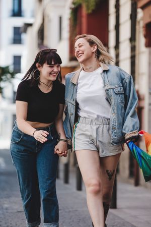 Lesbian couple with LGBT flag walking on street