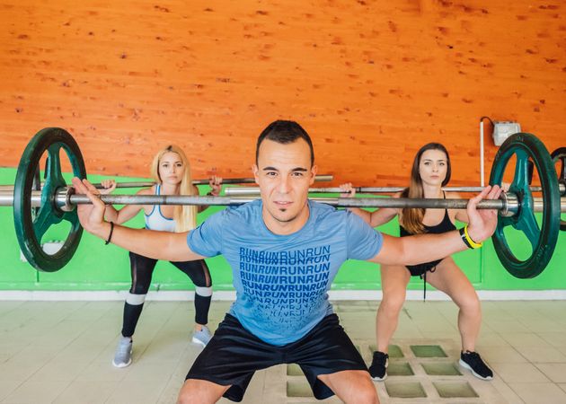 Athletes squatting with barbells in gym