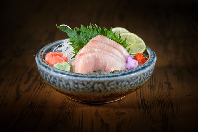 Bowl with delicious sashimi on wooden table