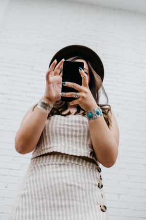 Woman in hat smiling browsing smartphone