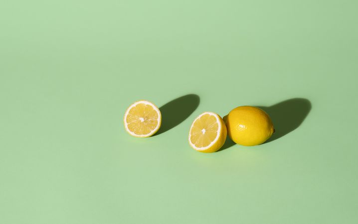 Fresh lemons cut in half on a green background