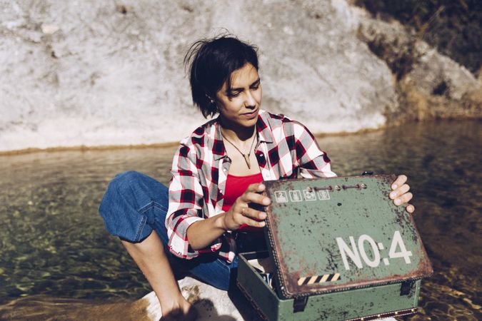Woman with picnic case on rock in water