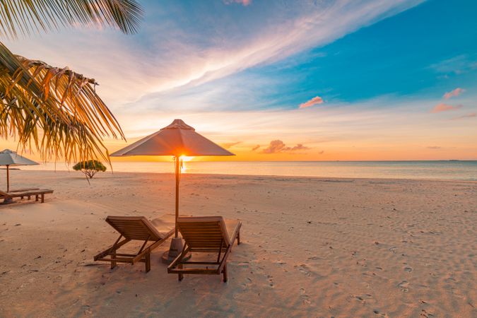 Colorful sunset on the beach with lounge chairs for relaxing