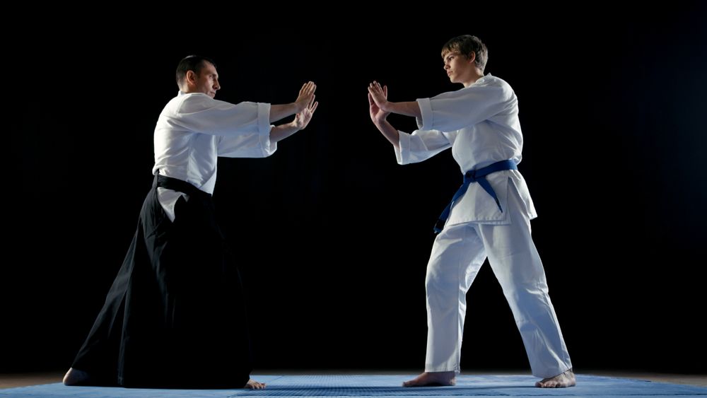 Martial Arts Master Wearing Traditional Samurai Hakamas and His Young Student Take Battle Stance.