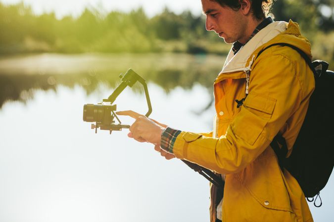 Side view of a man operating his digital camera mounted on gimbal