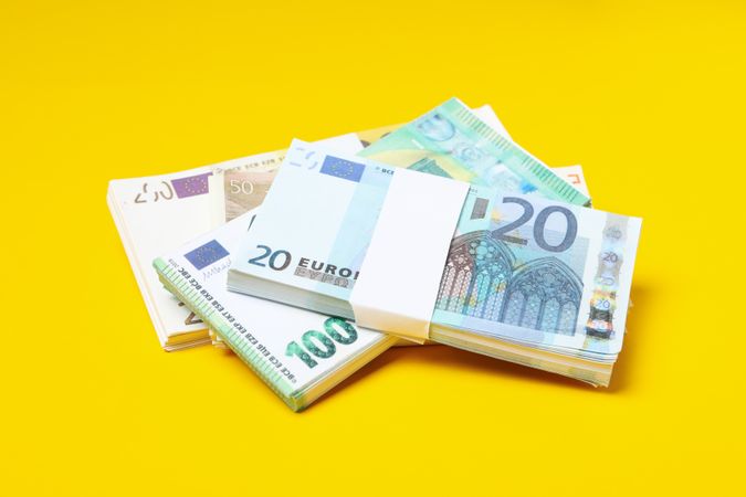 Many bundles of euros on a yellow background.
