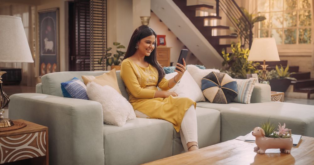 Woman Sitting On A Couch At Home, Using Smartphone Video Call To Chat With Her Family, Friends, Boyfriend.
