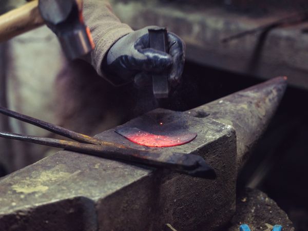 Crop man forging metal in smithy