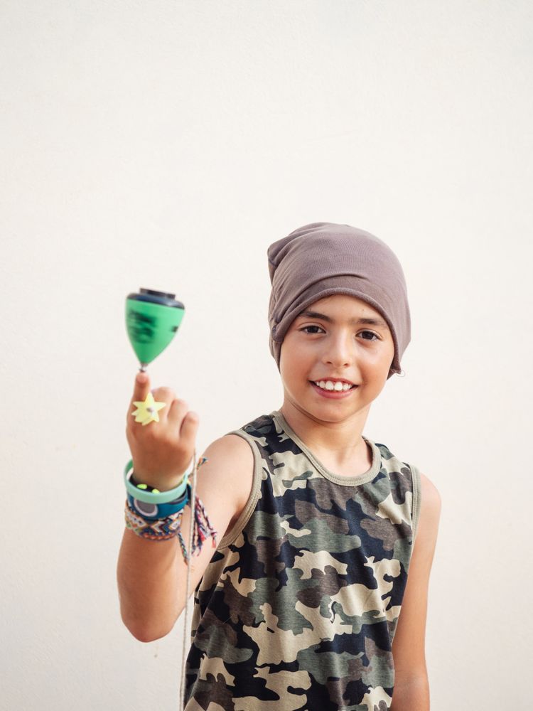 Smiling boy spinning tops on finger and looking at camera