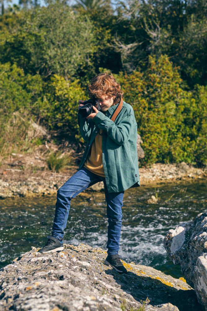 Focused boy taking photo on rocky coast