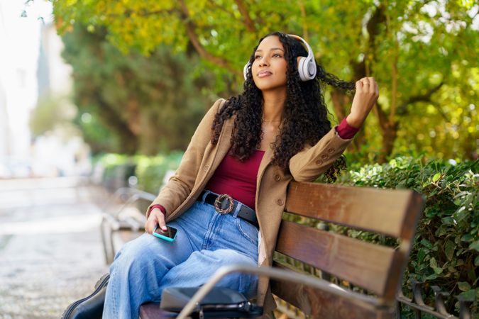A Young Woman Is Happily Enjoying Listening to Music While Relaxing in a Park on a Sunny Day